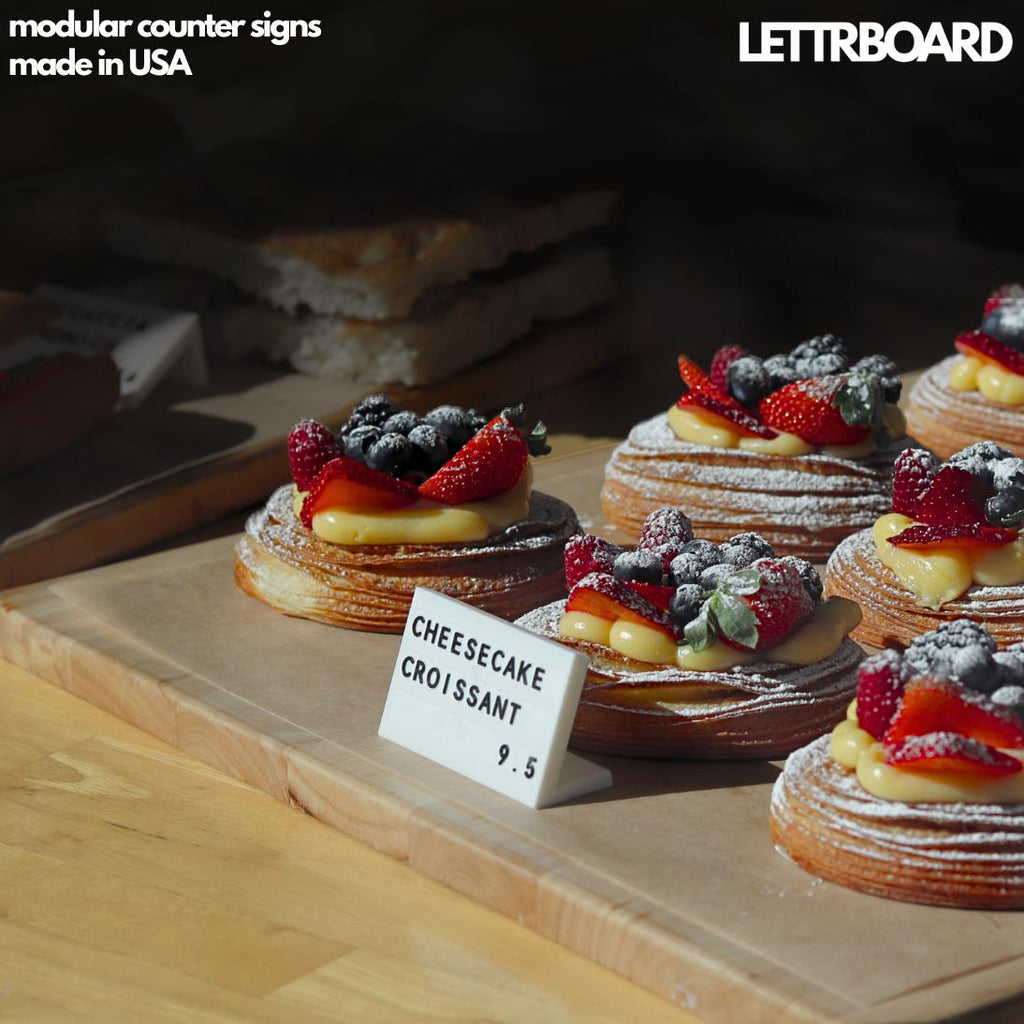 LettrBoard counter sign beside fruit-topped pastries in a bakery case