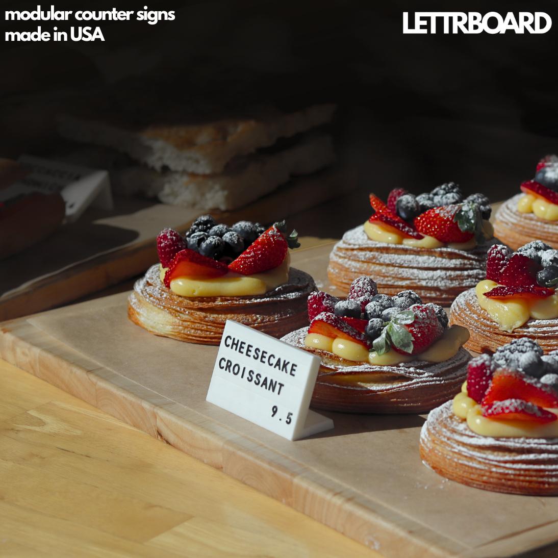 LettrBoard counter sign beside fruit-topped pastries in a bakery case