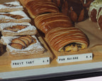 LettrBoard price signs labeling fruit tart and pain suisse in a bakery case